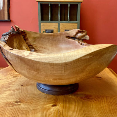A beautiful carved wood bowl on a wooden table.